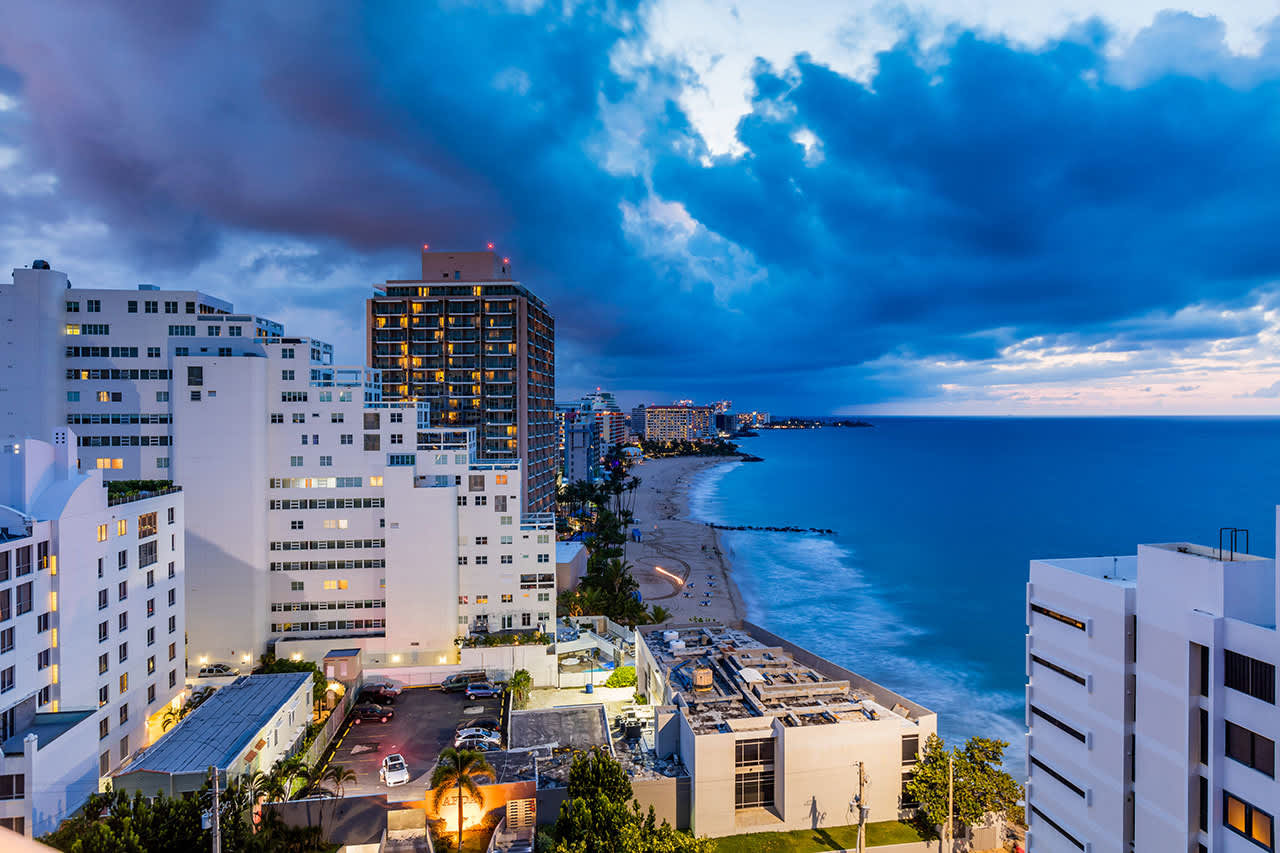 Condado beachfront at dusk with luxury condo towers illuminated along the Atlantic